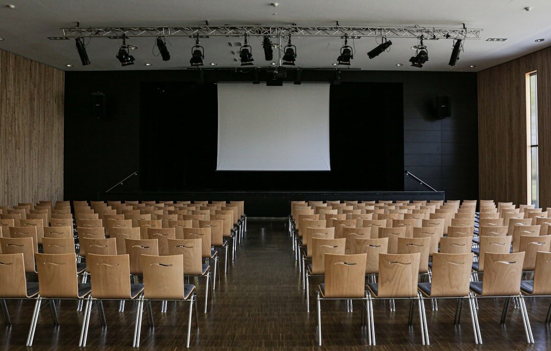 Modern conference hall with rows of chairs and speaker at podium